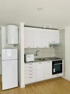 a kitchen with white cabinets and a white refrigerator at The apartment near the beach in Oeiras in Paço de Arcos