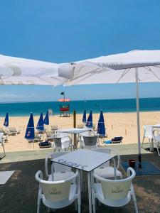 a beach with tables and chairs and umbrellas at The apartment near the beach in Oeiras in Paço de Arcos