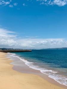 a beach with the ocean and a pier in the background at The apartment near the beach in Oeiras in Paço de Arcos