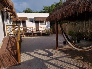a hammock outside of a building with a thatch roof at EncantaLuna in Holbox Island