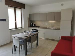 a kitchen with a table and chairs and a red couch at Cabà Holiday Bardolino Gritti in Bardolino