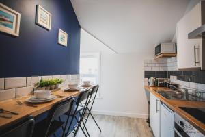 a kitchen with a table with chairs and a blue wall at St. Michael's Apartments in Bournemouth