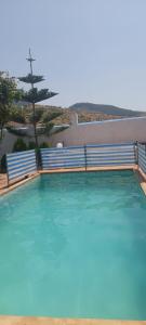 una gran piscina de agua azul con un árbol en el fondo en Dar ElBiad large family house en Ifargane
