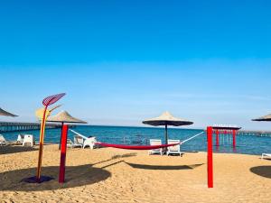einen Sandstrand mit Sonnenschirmen und einer Schaukel in der Unterkunft Blue Bay Asia Sokhna Aqua park بلو باي اسيا العين السخنه - عائلات فقط in Ain Suchna
