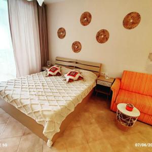 een slaapkamer met een bed en een oranje bank bij Студио Boho Green life Sozopol in Sozopol