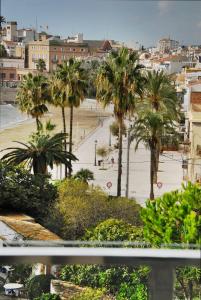 een uitzicht op een strand met palmbomen en een stad bij Apartaments Can Negret in Sitges
