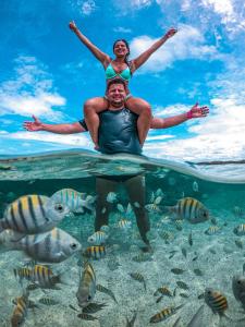 um homem e uma mulher nadando no oceano com peixes em Flats Sol e Mar em São José da Coroa Grande