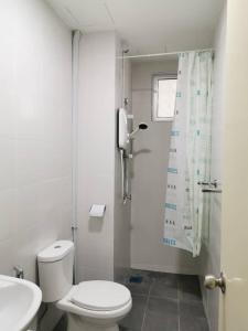 a white bathroom with a toilet and a shower at Taiping Comfort Condo Homestay in Taiping +6 photos