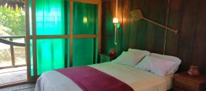 a bedroom with a bed with green walls and a window at Casa Kukama Lodge in Iquitos