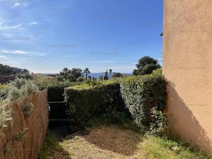eine Hecke vor einem Gebäude mit einem Zaun in der Unterkunft Rez-de-jardin T2 avec terrasse et parking - FR-1-100-284 in Rayol-Canadel-sur-Mer