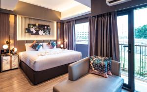 a hotel room with a bed and a chair at The One Smart Living in Bangkok