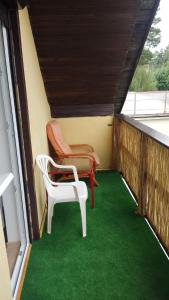 a balcony with two chairs and green carpet at Domek na Zaciszu in Rowy