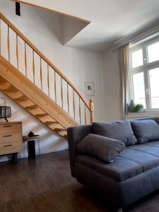 a living room with a couch and a staircase at Ferienwohnung Kamrath Altstadt von Neuruppin in Neuruppin
