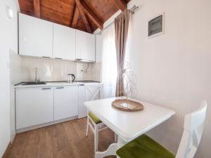 a kitchen with white cabinets and a white table and chairs at Harmonia Bungalows & Pool in Sveti Stefan