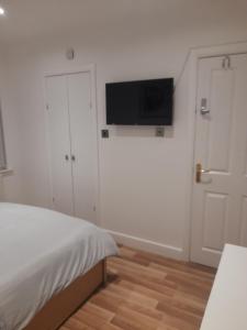 a bedroom with a bed and a flat screen tv on the wall at Lovely Home with full en-suite double bed rooms in Reading +15 photos