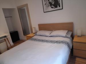 um quarto com uma cama branca e uma cabeceira em madeira em Lovely Home with full en-suite double bed rooms em Reading