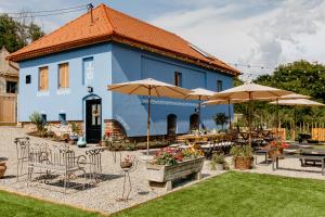 un edificio azul con mesas, sillas y sombrillas en ANNĂ DRAGĂ, en Colun