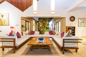 a living room with white couches and a wooden table at Villa Karang Berawa in Canggu