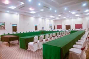 Chitwan Paradise Hotel في سوراها: قاعة مؤتمر بها طاولات خضراء وكراسي بيضاء