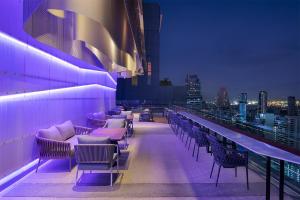 曼谷的住宿－Mode Sathorn Hotel - SHA Extra Plus，大楼内屋顶酒吧,配有桌椅