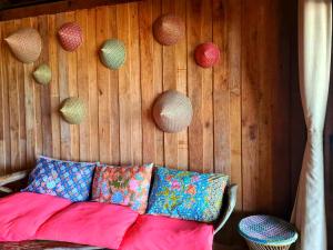 a couch with colorful pillows and decorations on a wooden wall at Lipe BeachHouse in Ko Lipe