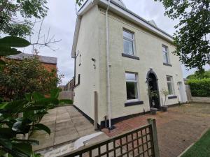 a white house with a fence in front of it at Milne Apartment 1 in Milnrow