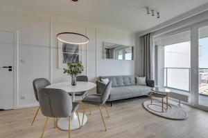 uma sala de estar com um sofá, uma mesa e cadeiras em Downtown Apartments Gdynia Modern Tower em Gdynia