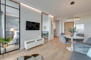 a living room with a table and a room with a bed at Downtown Apartments Gdynia Modern Tower in Gdynia