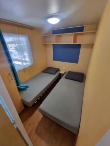 Habitación pequeña con 2 camas y ventana en Mobil-home 6 personnes climatisé le Miami en Saint-Chéron