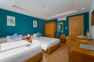 a bedroom with two beds and a desk with a laptop at Merry Land Hotel Da Nang in Danang