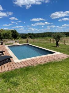 einen Pool im Garten mit Holzterrasse in der Unterkunft L Ecrin de Bricabeau Longère en pierres avec piscine privative in Saint-Méard-de-Gurçon