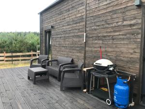 a patio with chairs and a grill and a building at Your Private Hytte in Smołdzino
