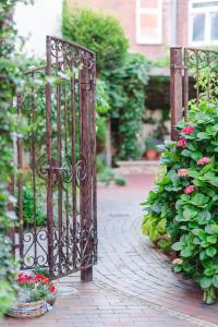 an iron gate in a garden with flowers at Romantik Hotel Reichshof in Norden