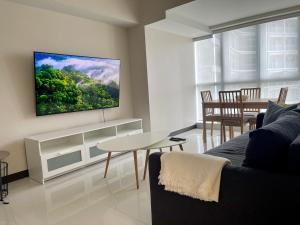 a living room with a couch and a tv on a wall at Bright 2-bedroom condo with pool in BGC Uptown in Manila