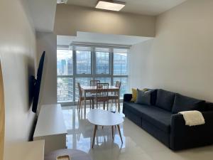 a living room with a couch and a table at Bright 2-bedroom condo with pool in BGC Uptown in Manila