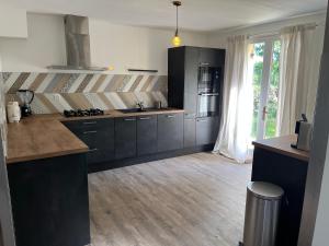 a kitchen with black cabinets and a large window at Villa Le grand Renard in Saint-Antoine-Cumond