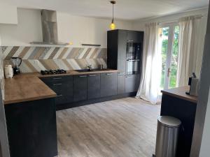 una cocina con armarios negros y una gran ventana en Villa Le grand Renard, en Saint-Antoine-Cumond