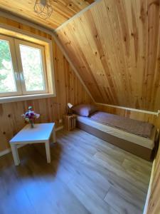 a bedroom in a log cabin with a bed and a table at Dolina Jelenia in Gorczyca