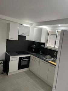 una cocina con armarios blancos y un aparato negro en App T2 a Montpellier, en Montpellier