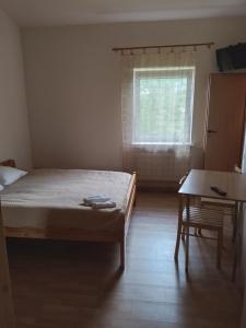 a bedroom with a bed and a table and a window at Trevena Kretinga in Kretinga