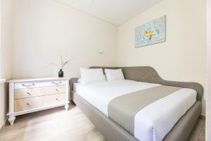 a white bedroom with a bed and a dresser at Lagūna - Šventoji in Šventoji