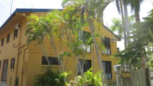 uma casa amarela com palmeiras em frente em Casual Lodge Unit 4 em Nelly Bay