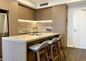 a kitchen with a sink and two bar stools at Luxury stunning riverview 1 bedroom apt 479F in Gold Coast