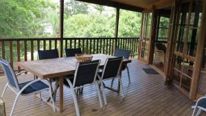 eine Holzterrasse mit einem Holztisch und Stühlen in der Unterkunft Kameruka in Arcadia