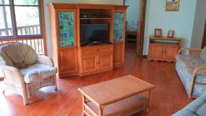 Una sala de estar con televisión y un centro de entretenimiento. en Kameruka, en Arcadia