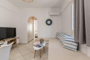 - un salon blanc avec une télévision et un canapé dans l'établissement GRotta Carpe Diem, à Naxos Chora