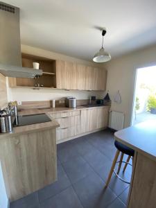 cocina con armarios de madera y encimera en Au coeur des volcans et lacs d'Auvergne en Saint-Beauzire