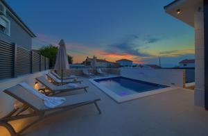 a patio with chairs and a swimming pool at dusk at Villa QUARNARO with heated pool in Omišalj