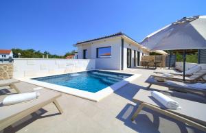 a swimming pool with chairs and an umbrella on a patio at Villa QUARNARO with heated pool in Omišalj
