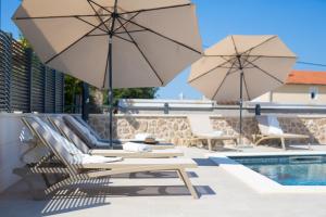 two chairs and umbrellas sitting next to a pool at Villa QUARNARO with heated pool in Omišalj +34 photos